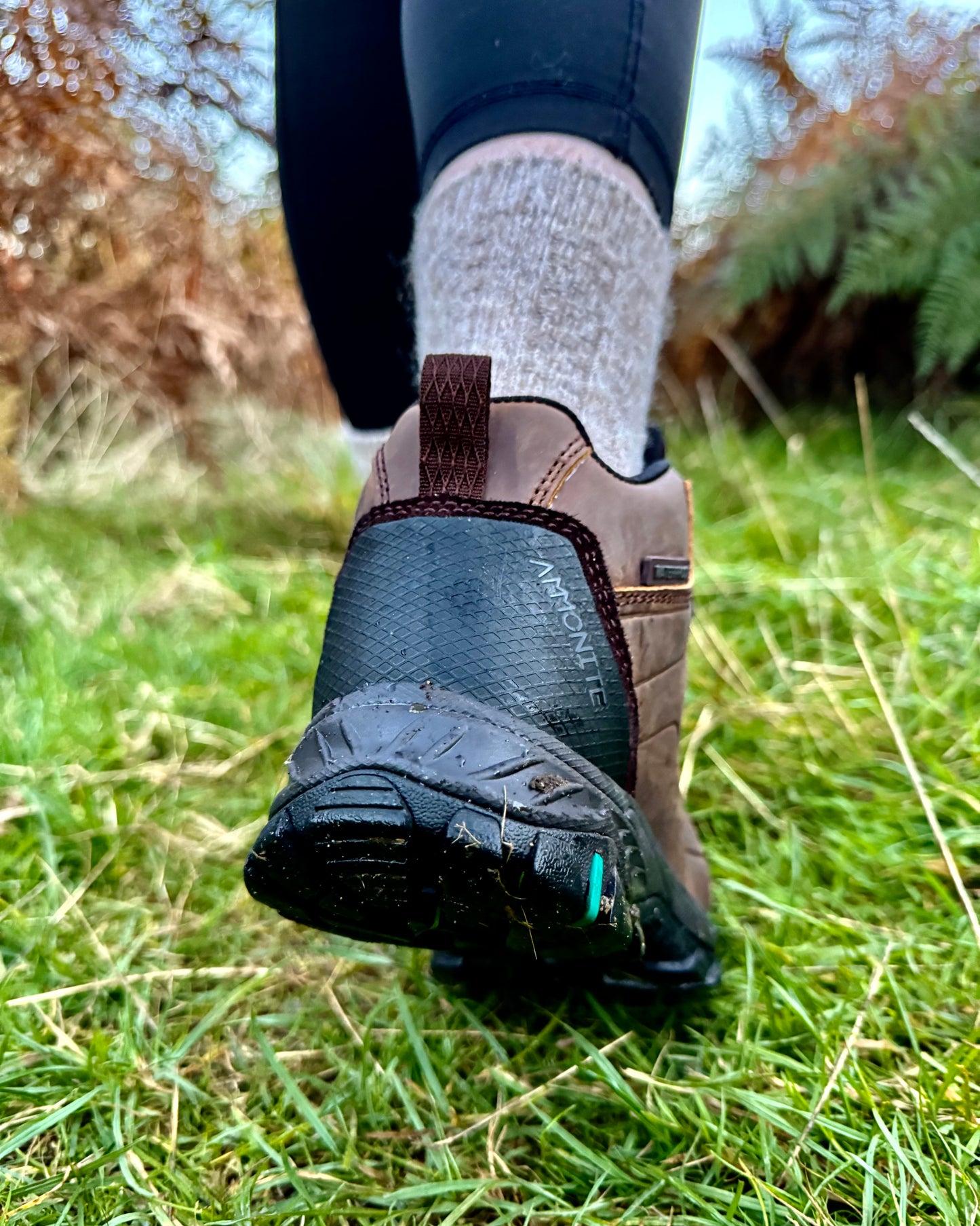 Back view of a woman wearing brown runswick hiking boots with a natural green background