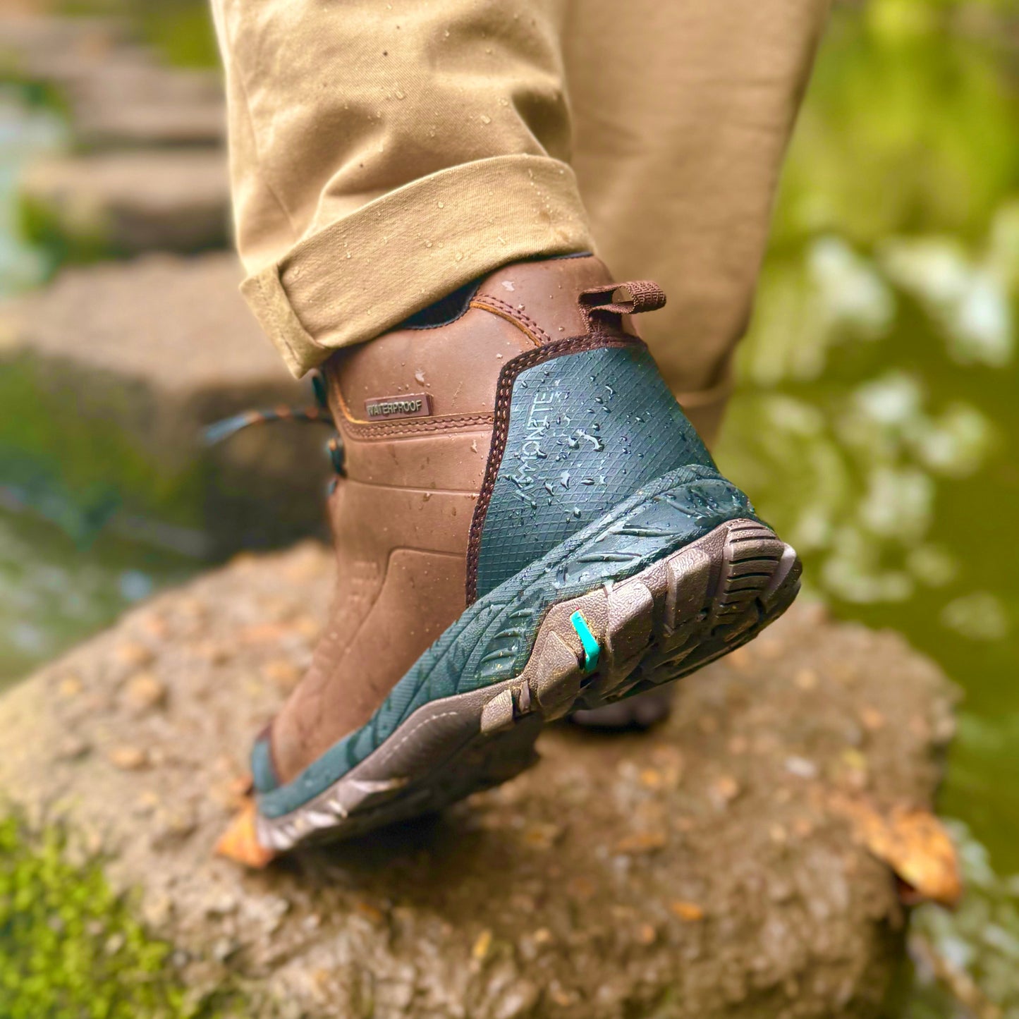 Person wearing brown hiking boots stepping onto a rock with a natural background