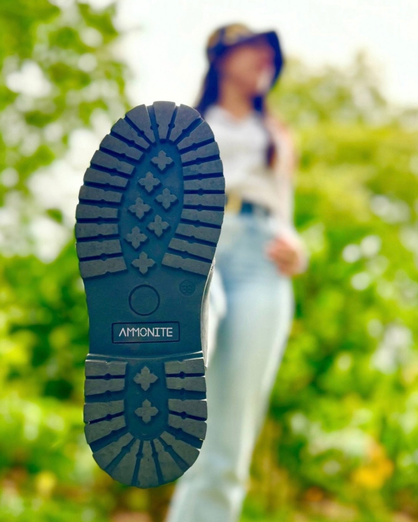 Close-up of a black portland all-terrain boot sole with a blurred person in the background.