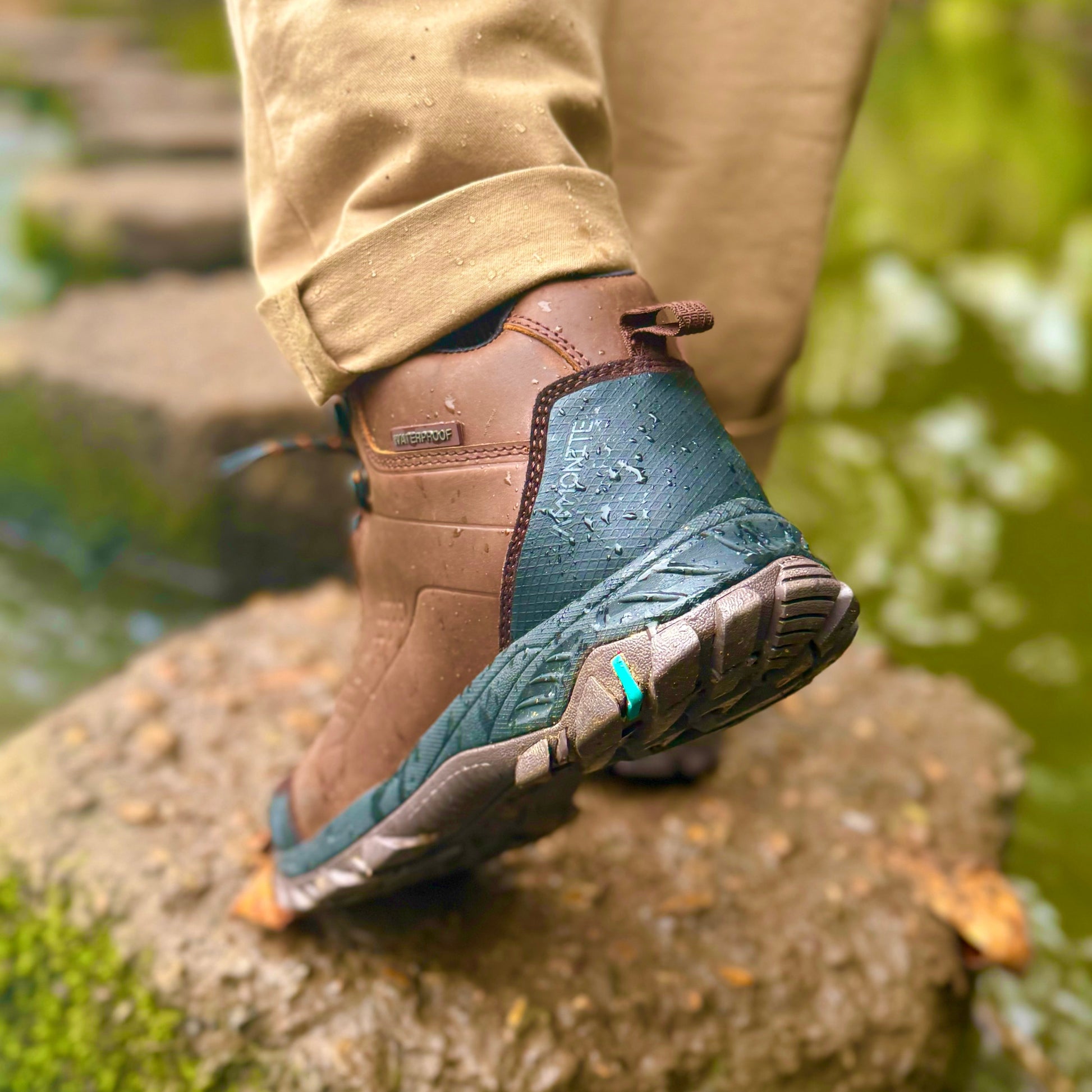 Person wearing brown hiking boots stepping onto a rock with a natural background